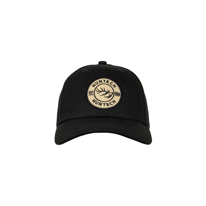 A black cap with an embroidered cream Huntech badge on the front, featuring a mid-profile fit with a curved peak.