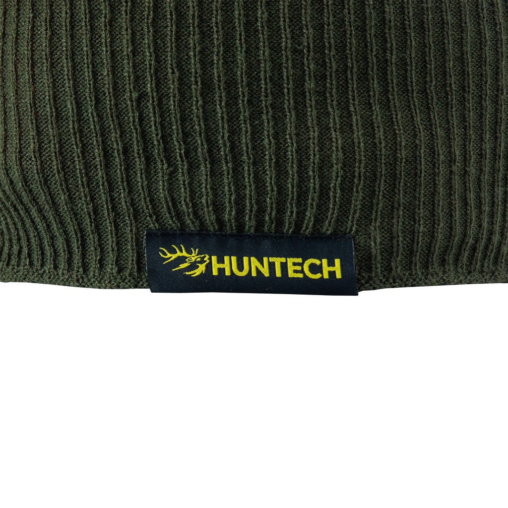 Close up of the Huntech logo in bright yellow on a black tag. Beanie is showing the military green side and has a military green lower edge.