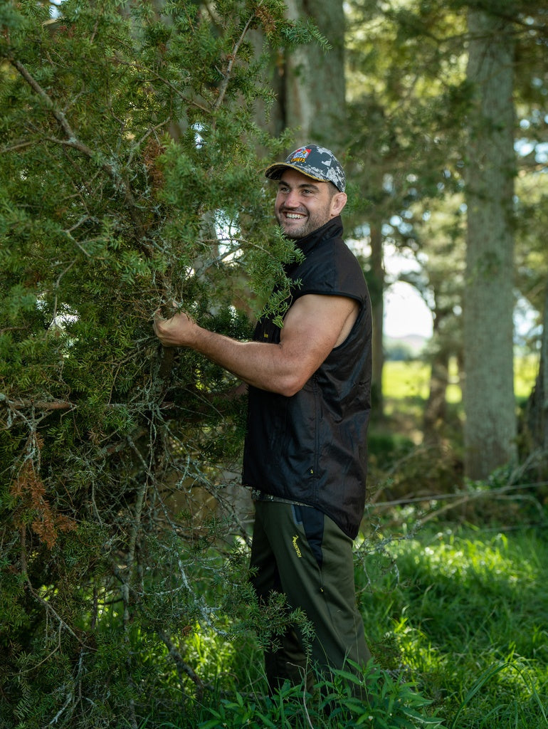 Image of smiling man wearing the oilskin vest while working to haul cut branches.