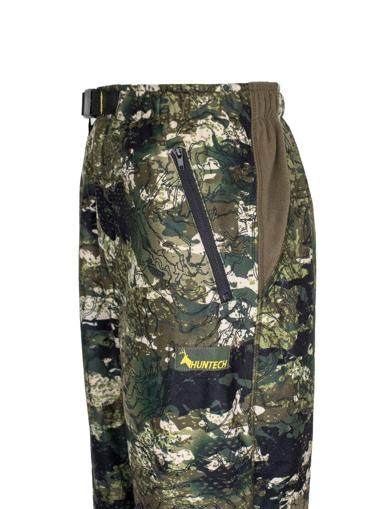 Close up of left hand side of men’s bush pant in 180gsm high grade anti-pill finished fleece with elasticated waistband and internal belt, twin hip zip pockets. Constructed using flatlock reinforced seams for strength and comfort, they features the Huntech logo on the left hand side just below the hip pocket. Shown in kakariki camo pattern. Ships from Australia.