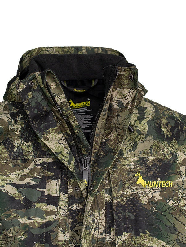 Close up of the zippered neckline of the jacket in kakariki camo pattern with Huntech logo in bright yellow to the right.