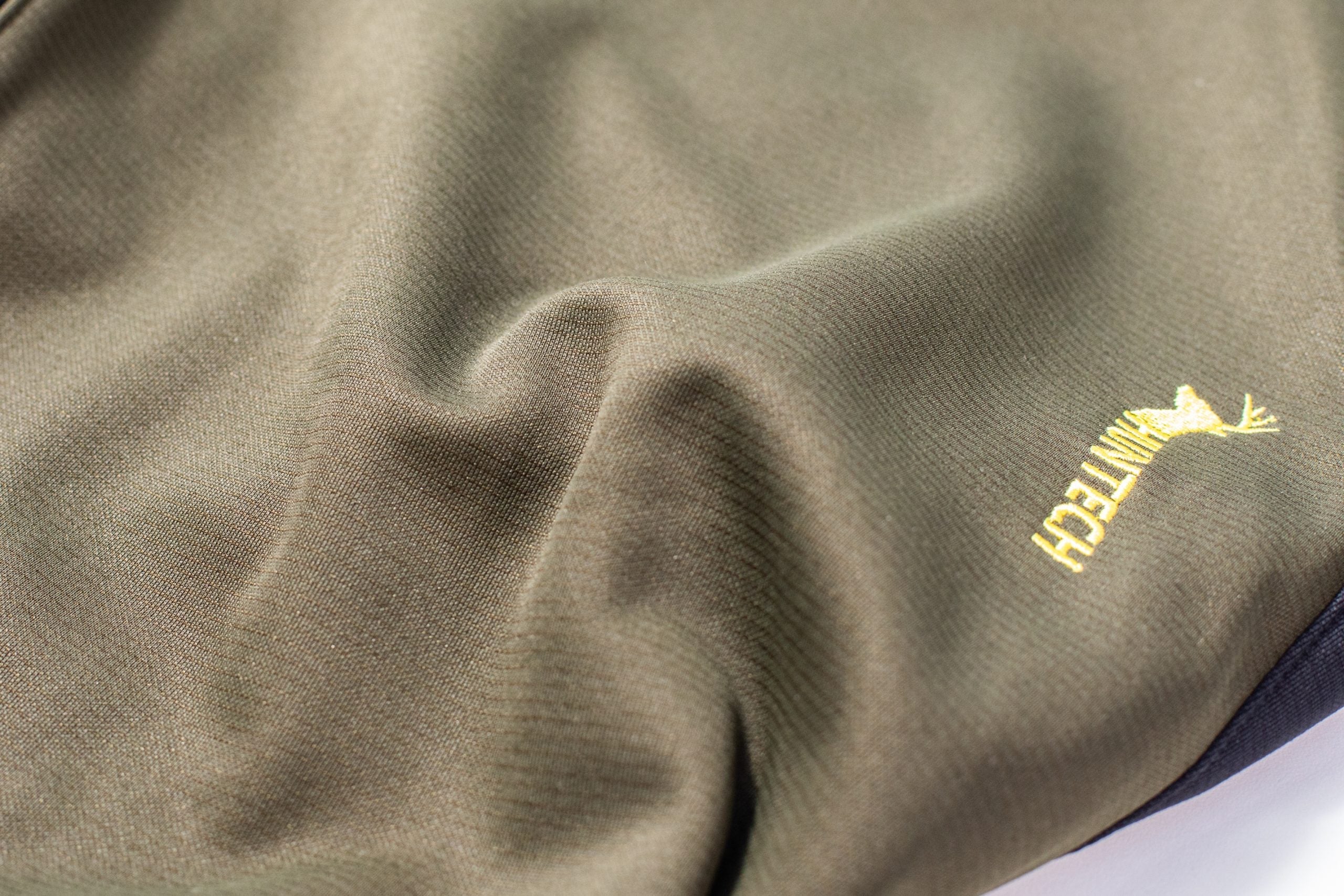 Close up of the exterior of the microform fabric with the Huntech logo in bright yellow showing. Made of a unique double face weave, the fabric offers you all the benefits and warmth of fleece on the inside.